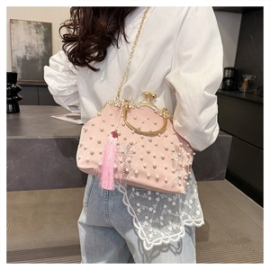 Detailed view of pink embroidered pearl bag with gold frame and silk tassel accent