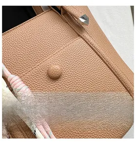 Gros plan sur la texture du cuir grainé marron et les coutures de ce sac seau