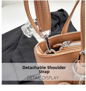 Détail de la boucle en métal argenté et de la bandoulière amovible sur sac en cuir caramel