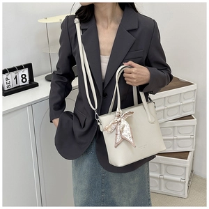Détail du sac seau en cuir crème avec foulard à cœurs roses et bandoulière longue