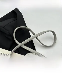Détail d'une bandoulière en cuir gris clair à grain litchi avec couture fine pour sac chic