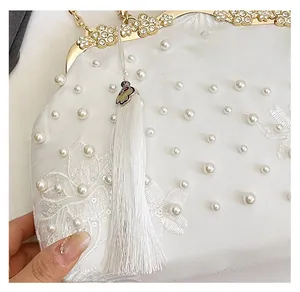 Macro detail of embroidered floral textures with pearls and silk tassels on evening bag