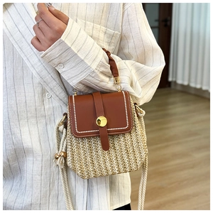 Dettaglio della borsa in paglia con patta in pelle e ornamento con nappa intrecciata
