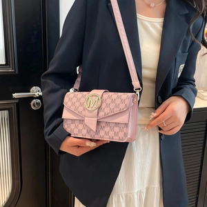 Pink underarm bag with letter M pattern and golden buckle on stylish model outfit
