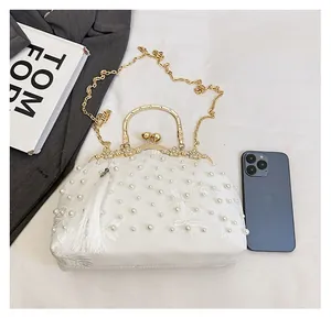 Detailed macro view of white lace floral embroidery and faux pearls on the evening bag