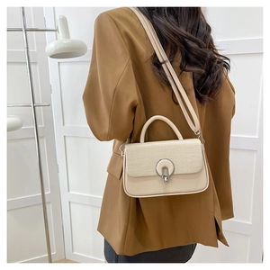 Beige PU leather crossbody bag with woven texture flap and silver metal buckle worn by model