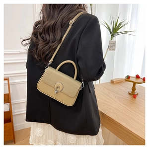 Detail of beige woven patchwork handbag with round silver buckle and smooth leather base