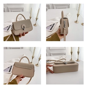 Detail of a beige handbag with woven flap texture and circular silver twist lock