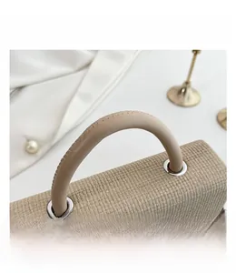 Macro detail of beige woven texture handbag with silver ring hardware and sturdy handle