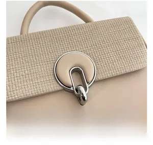 Macro detail of beige handbag featuring textured woven fabric and silver ring metal clasp