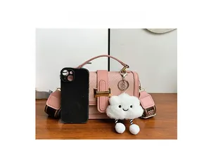 Pink crossbody bag with gold hardware and wide strap shown next to phone for size scale