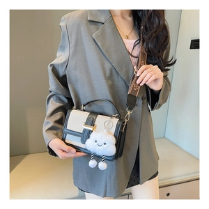 Detail of contrast stitch handbag with vintage pattern strap and plush charm