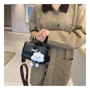 Detail of contrast color crossbody bag featuring gold H-buckle and cloud charm accessory