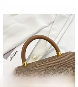 Detail of brown woven box bag with leather handle and gold H logo on textured fabric