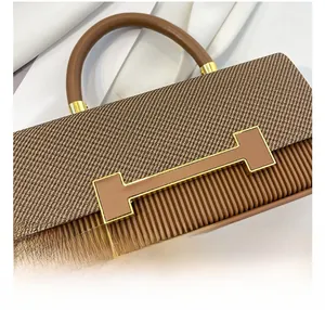 Close-up of brown box bag with twill fabric, wavy pleated texture and golden H-shaped clasp