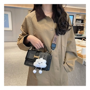 Detail of color-block crossbody bag with gold H-buckle and cute cloud charm accessory
