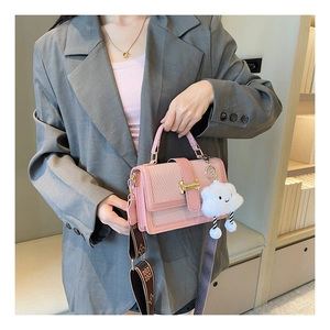 Detail of pink woven crossbody bag with gold lock, white cloud charm and patterned strap