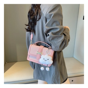 Detail of pink woven crossbody bag with gold buckle and cute cloud pendant on model