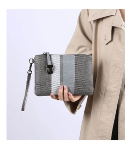 Close-up of a striped woven clutch bag with high-quality tweed texture and metal snap button