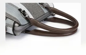Detail of woven fabric handbag with brown PU handles and silver metal zipper closure