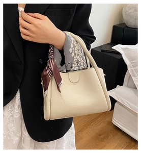 Dettaglio della borsa a secchiello in pelle martellata bianco crema con foulard a righe