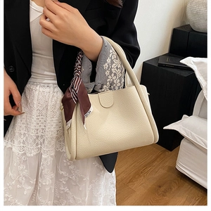 Dettaglio della borsa a secchiello in pelle martellata con foulard in seta sul manico