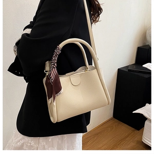 Dettaglio borsa a secchiello color crema in pelle martellata con foulard di seta a righe