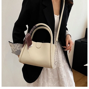 Dettaglio della borsa a secchiello bianco panna in pelle con foulard decorativo