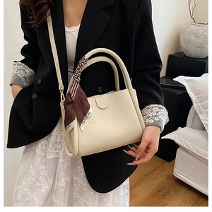 Dettaglio della borsa a secchiello off-white con trama litchi e foulard di seta moda