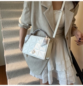 Detailed view of white quilted bag with scarf-wrapped handle and metal twist lock