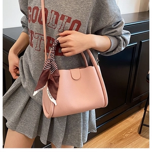Dettaglio della pelle martellata rosa di una borsa con foulard di seta alla moda