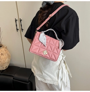 Pink quilted shoulder bag with metal lock and paisley scarf handle detail on a model