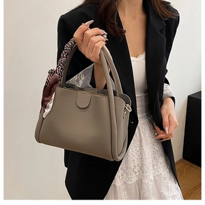 Dettaglio della borsa a secchiello in pelle taupe con foulard in seta sul manico