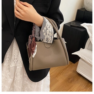 Dettaglio della borsa a secchiello in pelle martellata marrone con foulard di seta geometrico