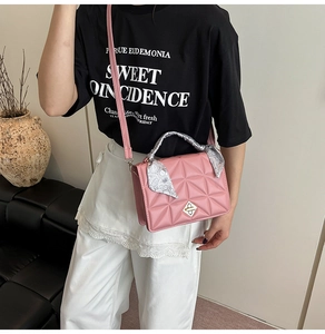 Detail of pink quilted shoulder bag with scarf-wrapped handle and silver turn-lock