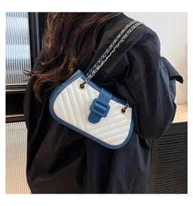 Detail of blue and white quilted crossbody bag with gold chain strap on model