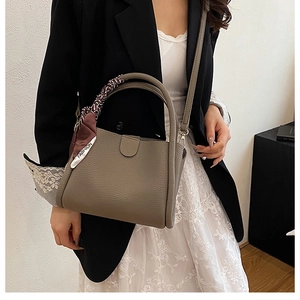 Secchiello in pelle taupe con foulard decorativo indossato da modella con blazer nero
