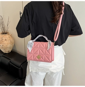 Macro shot of pink quilted leather bag with golden geometric lock and silk scarf handle