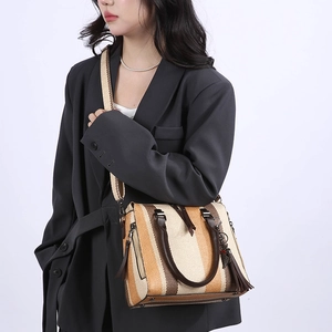 Three-tone striped woven tote bag with wide strap and tassel worn by a model