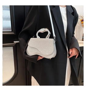 Dettaglio borsa con paillettes argento, manico in metallo a cuore e base in pelle