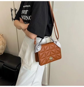 Detail of a brown quilted handbag with a gold lock and decorative floral scarf on handle