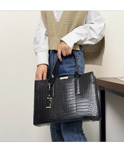 Close-up of black crocodile pattern tote bag with gold metal buckle and sturdy bottom studs