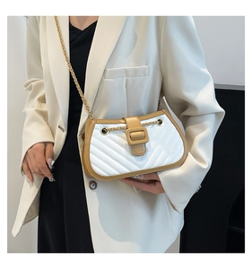 Detail of color-block quilted shoulder bag with gold chain strap on white blazer