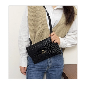 Detailed close-up of black crocodile pattern crossbody bag showing the gold magnetic buckle