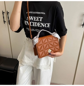 Close-up of brown geometric quilted handbag featuring a gold clasp and silk scarf handle