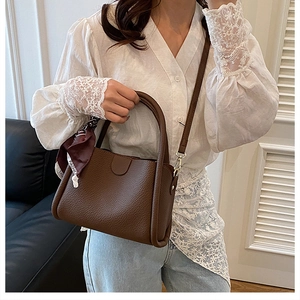 Dettaglio della borsa tote in pelle marrone scuro con foulard decorativo e rivetti in metallo