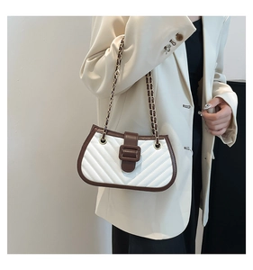Close-up of quilted white leather cross-body bag with brown buckle and chain strap