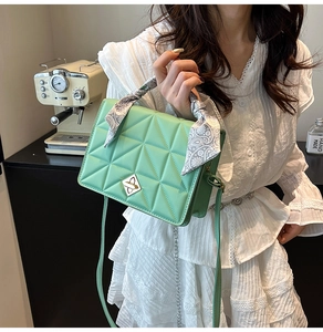 Detail of mint green quilted handbag with silk scarf handle and metal turn-lock closure