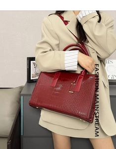 Detail of burgundy crocodile pattern tote bag featuring gold base studs and glossy finish