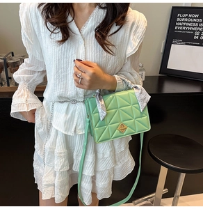 Detail of mint green quilted crossbody bag featuring golden diamond clasp and scarf handle
